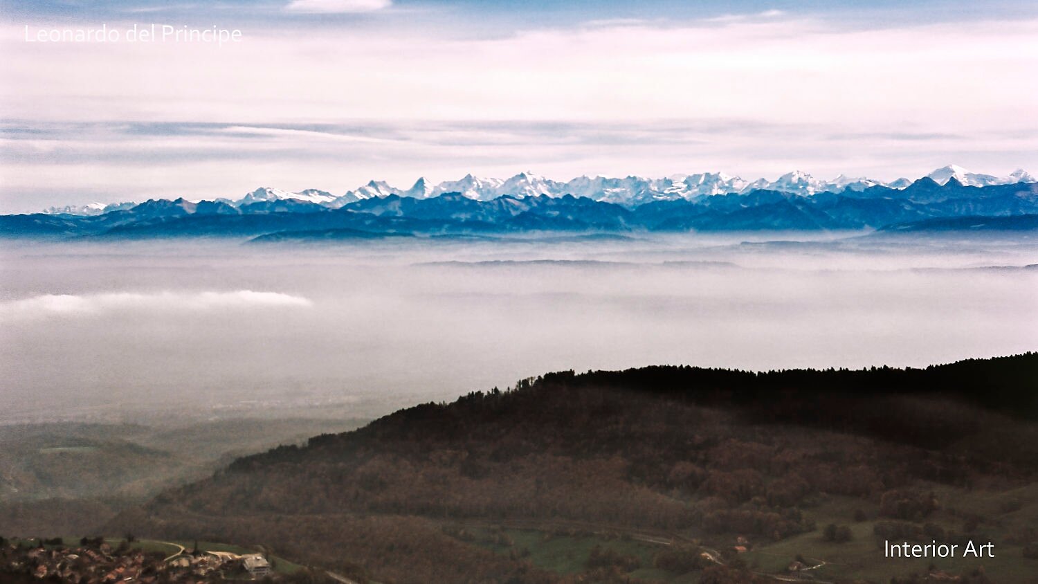 HBSD05 Mountain landscape with snow-capped peaks under a bright sky, distant mist below, and dark rolling hills in the foreground, creating a serene atmosphere.