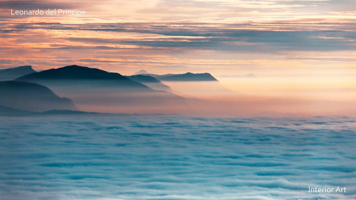 PUMO01 Serene mountain landscape photography with peaks rising above a sea of clouds, under a pastel dawn sky. Soft hues of blue and orange.