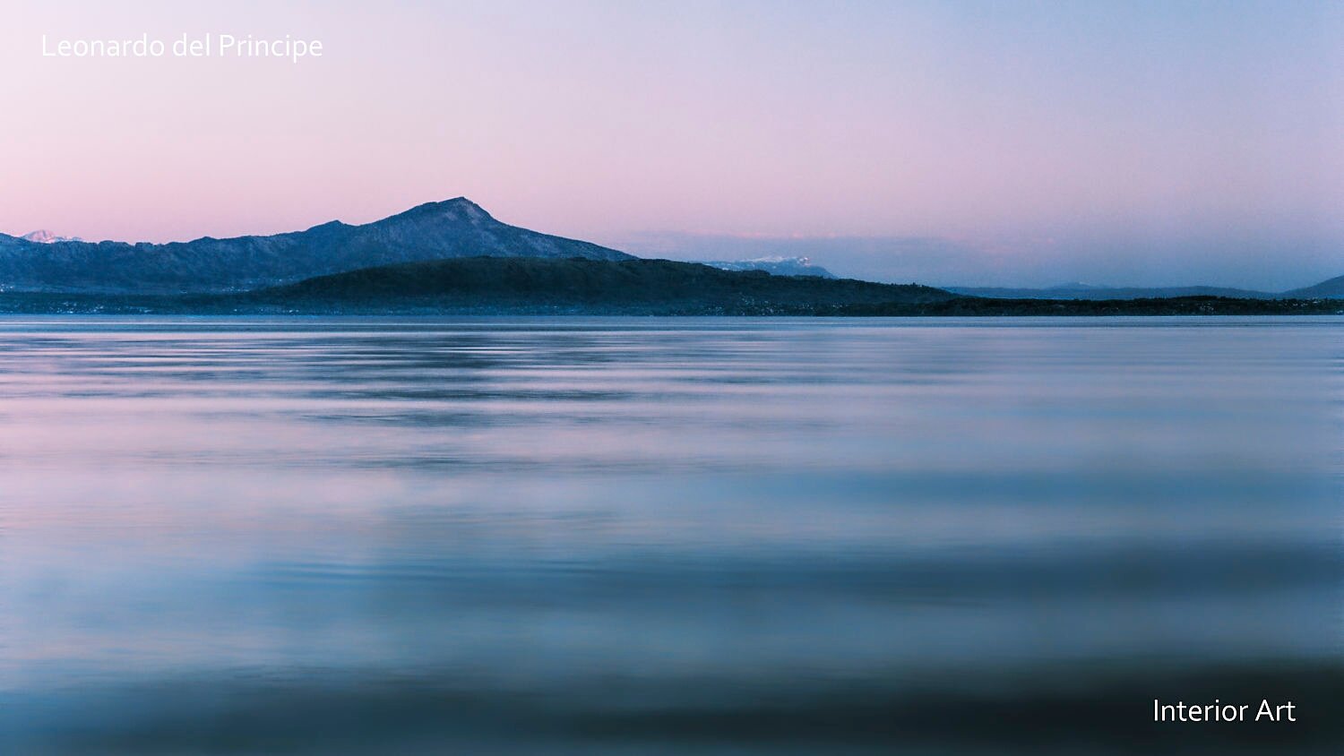 WFNF01 Calm lake with soft ripples reflecting a pastel sky at dusk, mountains silhouetted in the distance. Tranquil and serene dusk atmosphere.