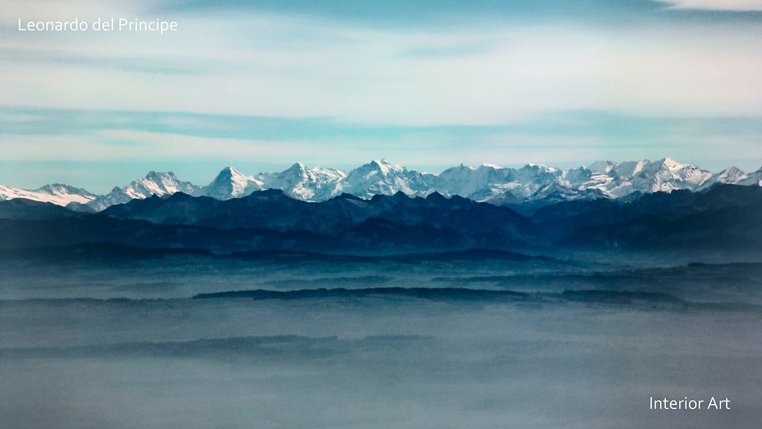 HBSD03 Panoramic view of distant snow-capped mountain range under a pale blue sky. Soft mist lingers over dark hills, creating a serene and tranquil scene.