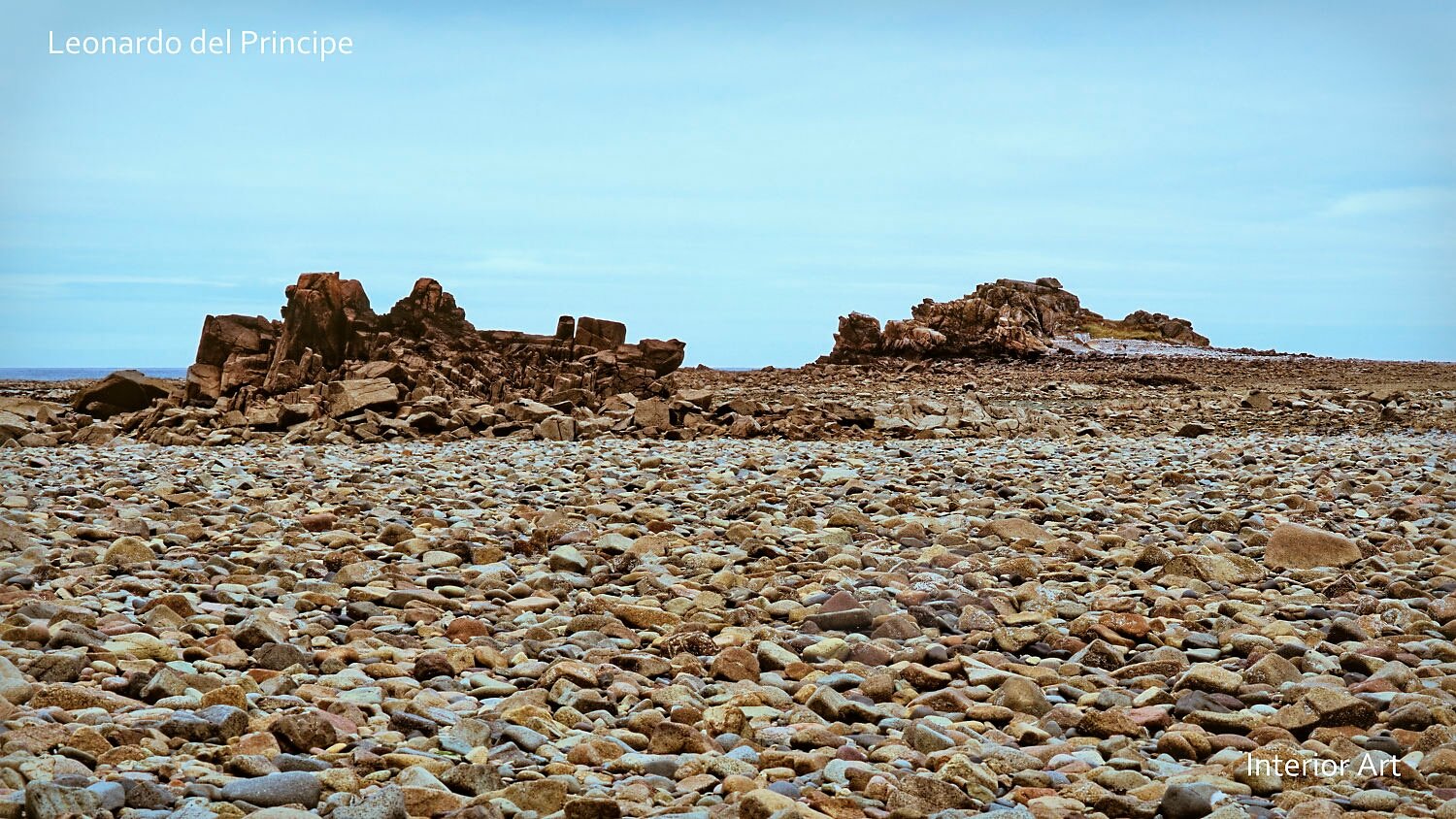 MORG04 Rocky seashore landscape with scattered stones and jagged rock formations under a cloudy sky. The scene conveys a rugged, serene, and monumental atmosphere.